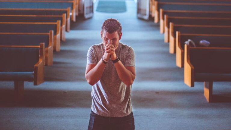 homem de joelho orando na igreja